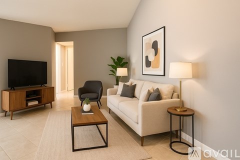 A living room with a white couch, a wooden coffee table, a black chair, a flat-screen TV, and a potted plant.