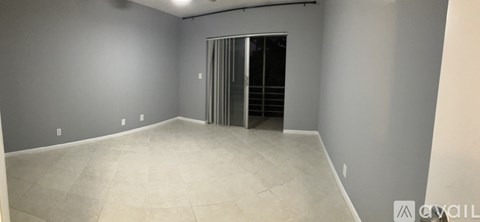 A room with a grey wall and a white floor with a door on the right side.