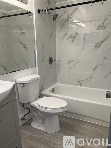 A white toilet is in a bathroom with marble tile walls.