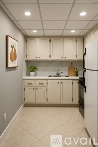 A kitchen with white cabinets and a fridge.