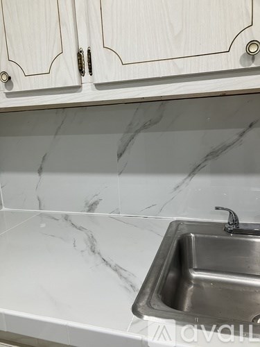 A white sink is installed in a marble countertop.