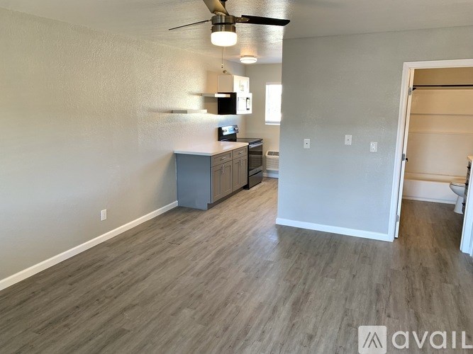 A room with a ceiling fan and a cabinet with a microwave.
