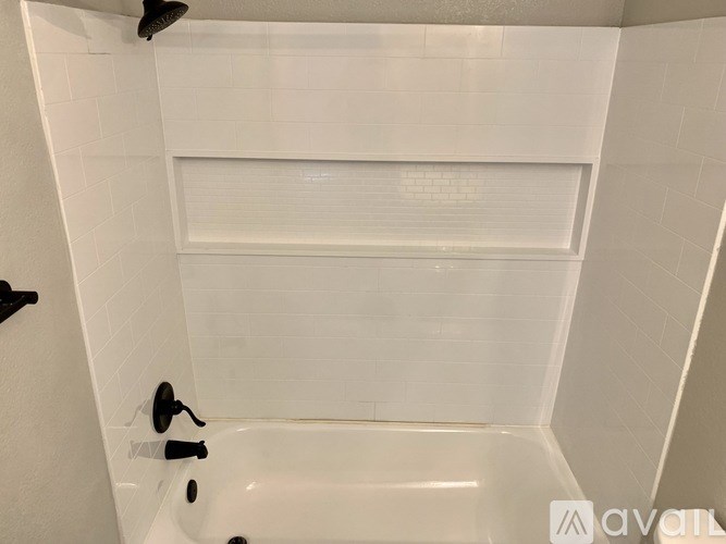 A white bathroom with a tub and a shower head.