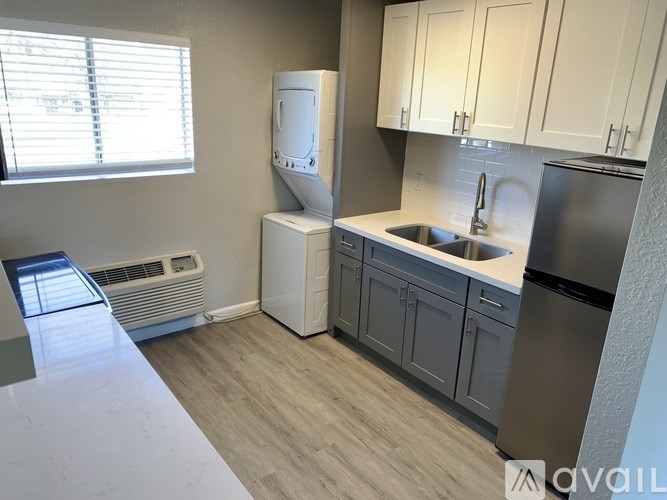 A kitchen with a stainless steel refrigerator, a white dishwasher, and white cabinets.