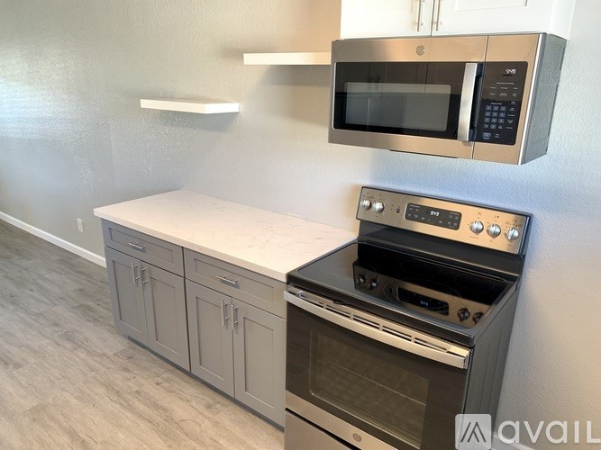 A kitchen with a microwave oven mounted on the wall and a stove below it.