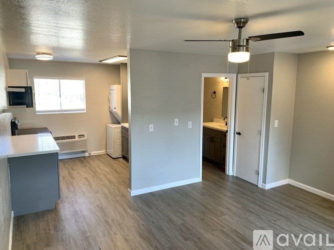 A spacious room with a kitchen area and a ceiling fan.