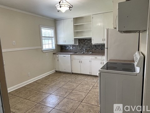 A kitchen with white cabinets and a tiled floor.