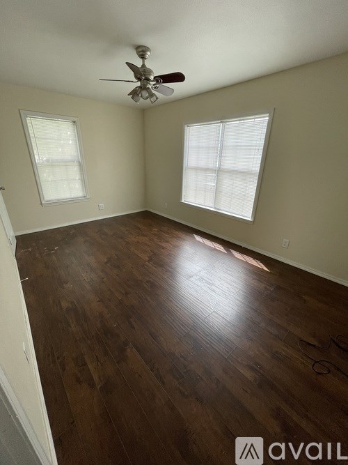 A room with a ceiling fan and wooden flooring.