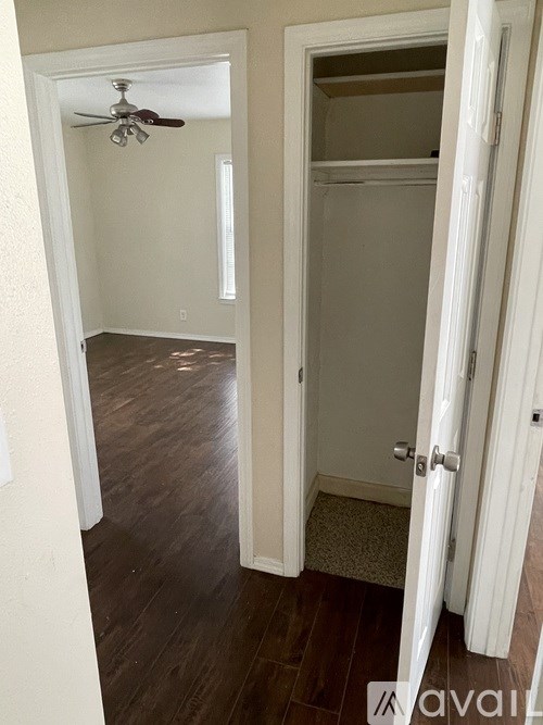 A room with a ceiling fan and a door leading to another room.