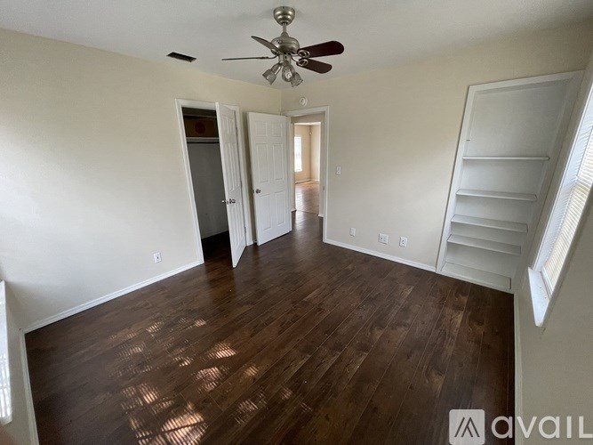 A room with a ceiling fan and wooden flooring.