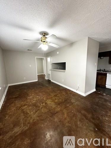 A room with a ceiling fan and brown flooring.