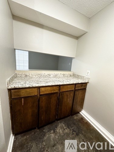 A room with a granite countertop and wooden cabinets.