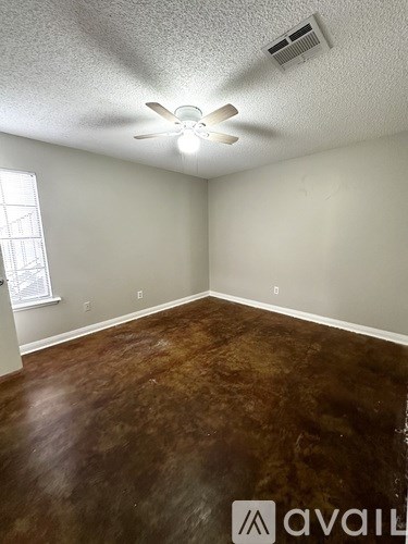 A room with a ceiling fan and brown flooring.