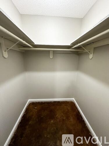 A small, empty room with a brown floor and white walls.