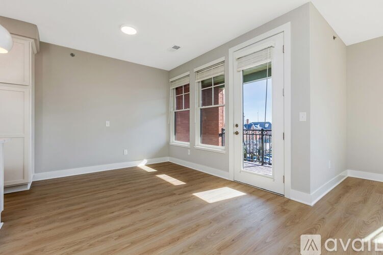 A room with wooden floors and a door leading to a balcony.