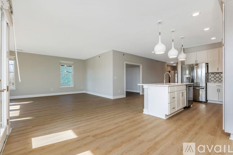 A spacious kitchen and living room with wooden floors and white cabinetry.