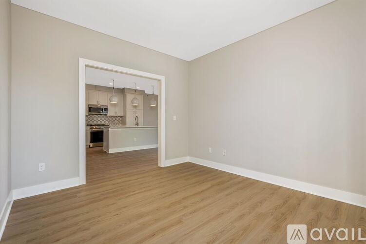 A room with wooden flooring and a white doorway leading to another room.
