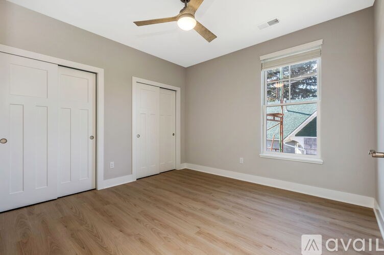 A room with a ceiling fan and a window showing an outdoor view.