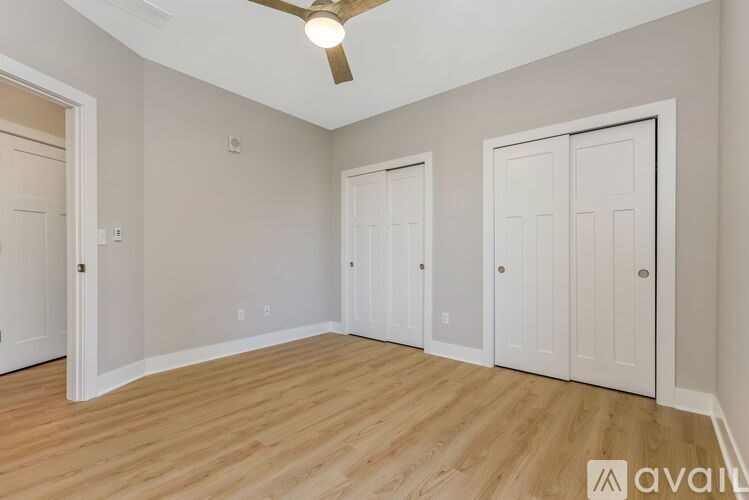 A room with a ceiling fan and three doors.