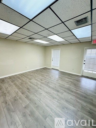 A spacious room with wooden flooring and a skylight.