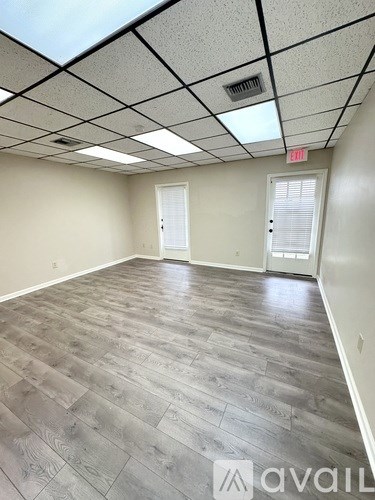 A spacious room with wooden flooring and white walls.