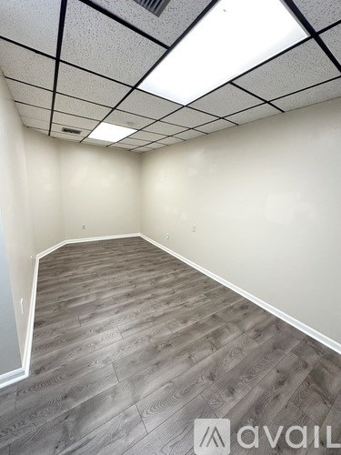A room with wooden flooring and a white ceiling with square tiles.
