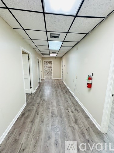 A long hallway with wood floors and a fire extinguisher on the wall.