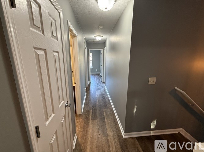 A hallway with a wooden floor and white walls.