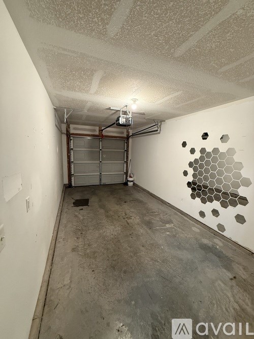 A room with a white wall and a grey floor with a honeycomb pattern on the wall.