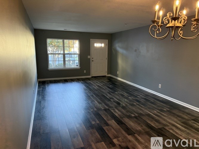 A room with wooden flooring and a chandelier.