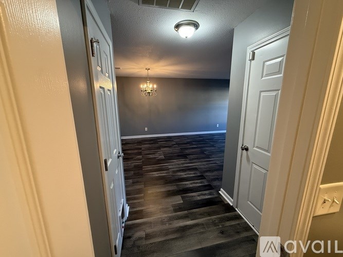 A hallway with a chandelier and a door on the right.