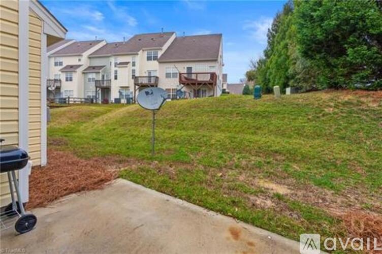 A grassy area with a satellite dish and a house in the background.