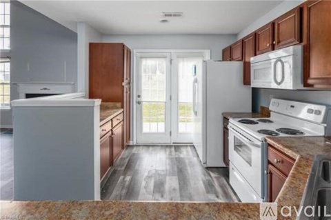 A kitchen with white appliances and wooden cabinets.