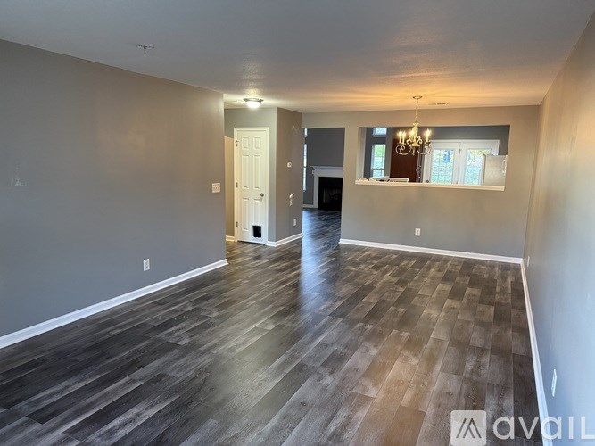 A spacious room with wooden flooring and a chandelier.