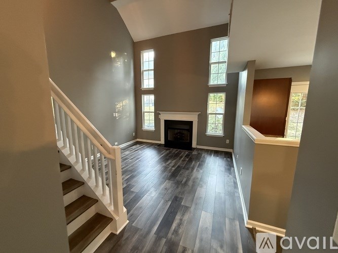 A spacious living room with a fireplace and a staircase.