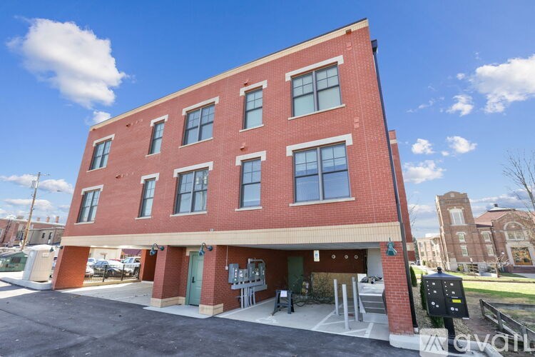 A red brick building with a green door and windows.