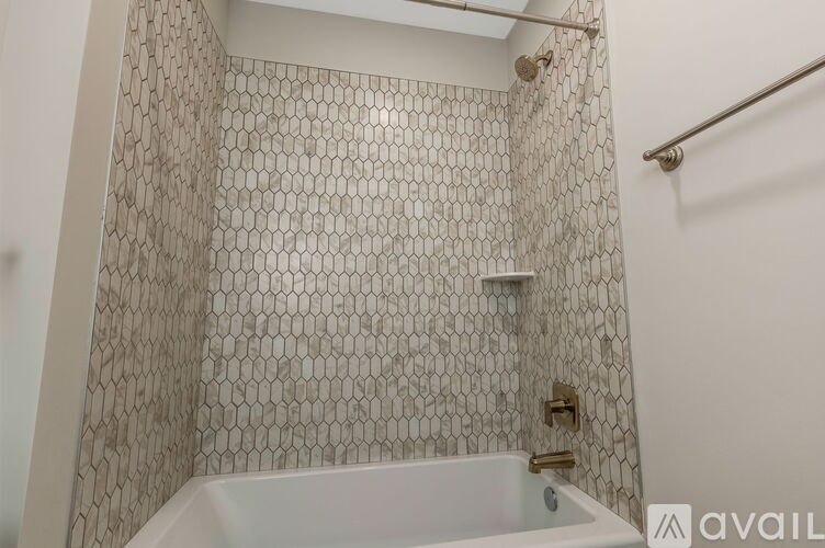 A white bathtub sits in a bathroom with a tiled shower.
