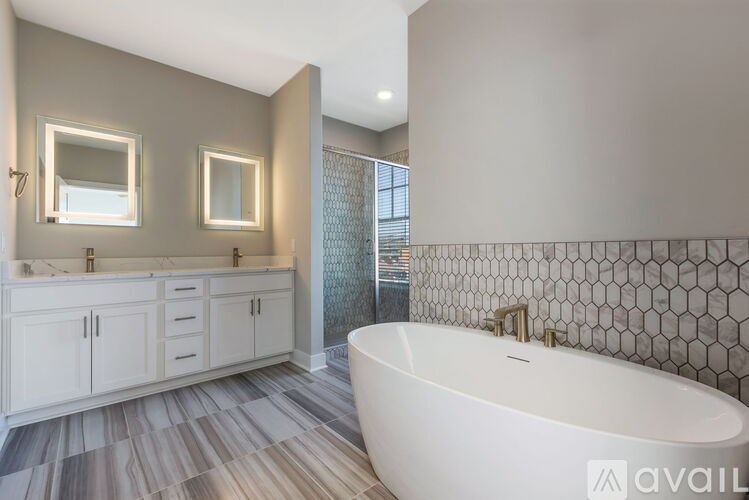 A modern bathroom with a white tub and grey tiles.