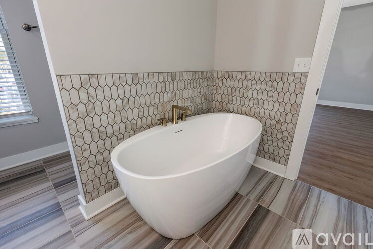 A white bathtub is in a bathroom with a tiled wall.