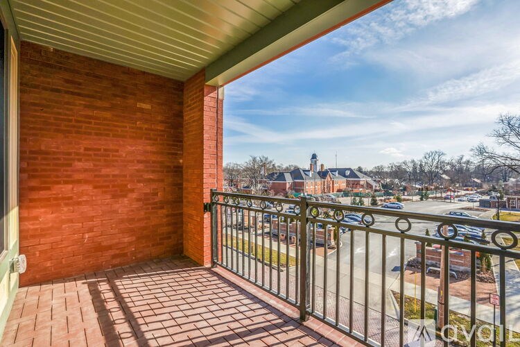 A balcony with a metal railing overlooks a street with cars and buildings.