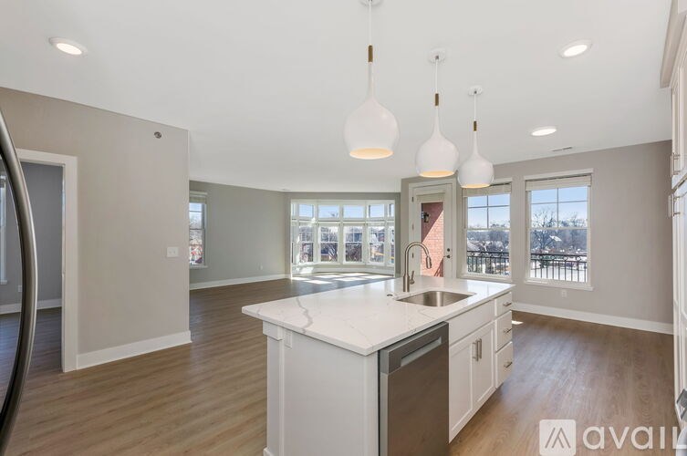 A modern kitchen with a large island and pendant lights.