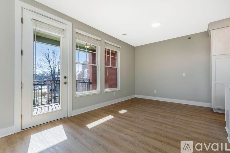 A room with a white door and a window with a view of a tree and a building outside.