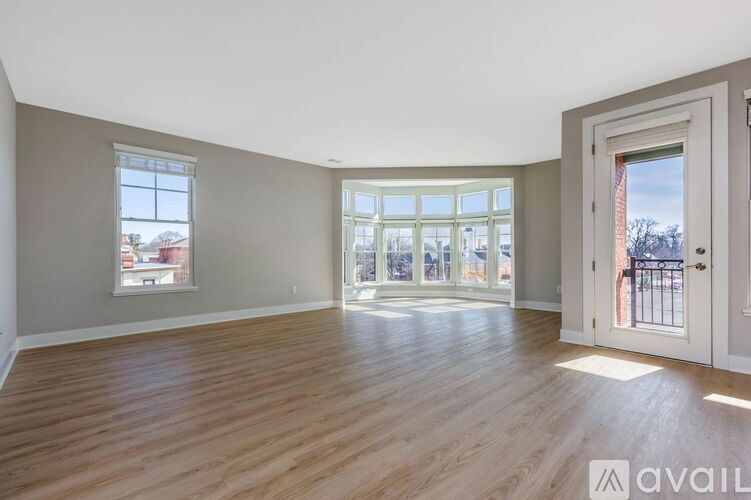 A spacious room with wooden flooring and large windows.