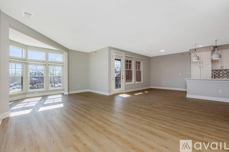 A spacious room with wooden flooring and large windows.