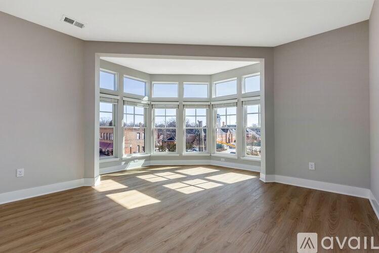 A spacious room with wooden floors and large windows overlooking a cityscape.
