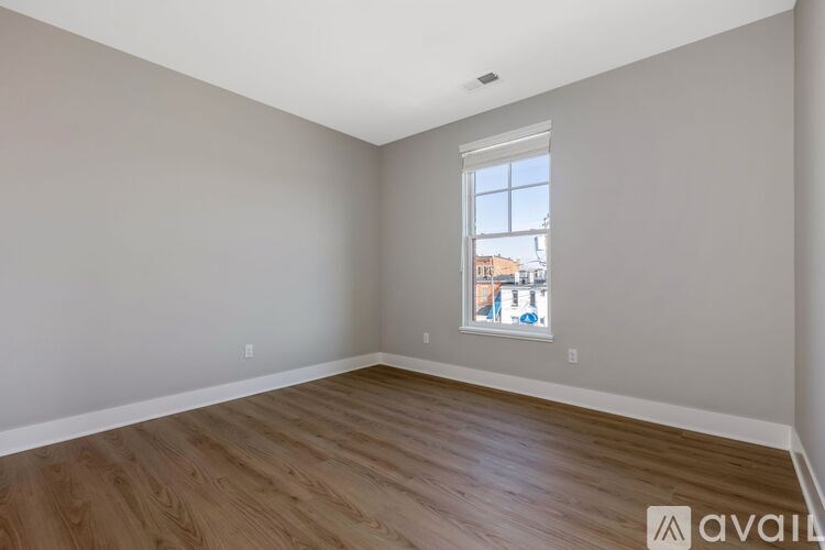 A room with wooden flooring and a window showing a cityscape outside.