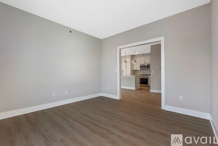 A room with wooden flooring and a white doorway leading to another room.