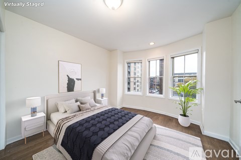 A bedroom with a large bed and a plant on the windowsill.