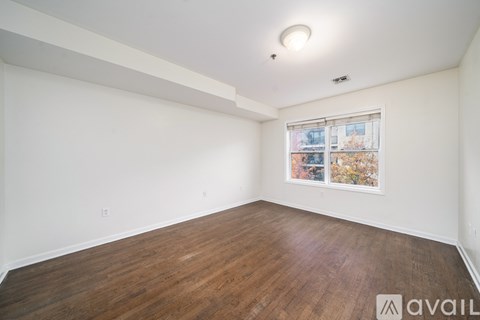 A room with wooden flooring and a window with a view of a cityscape.