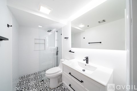 A bathroom with a toilet, sink, and mirror.